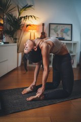 Beautiful young woman practicing yoga at home making Camel Pose on yoga mat, Exercises for strength, balance and flexibility, Body Care Morning Yoga Routine Concept