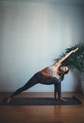 Vertical photo of young happy woman training yoga at home making extended side angle pose, Full Body Stretching Workout At Home