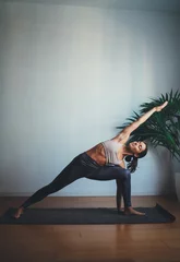 Fototapeten Vertical photo of young happy woman training yoga at home making extended side angle pose, Full Body Stretching Workout At Home © iana_kolesnikova