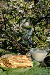 Delicious thin pancakes with creme on wooden table, flat lay. Homemade dessert. Shooting in garden outdoors. 
