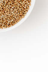 Bowl of uncooked buckwheat grains on white isolated background