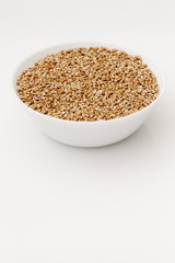 Bowl of uncooked buckwheat grains on white isolated background