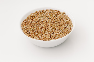 Bowl of uncooked buckwheat grains on white isolated background