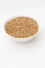 Bowl of uncooked buckwheat grains on white isolated background
