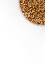 Bowl of uncooked buckwheat grains on white isolated background
