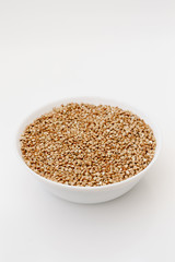 Bowl of uncooked buckwheat grains on white isolated background