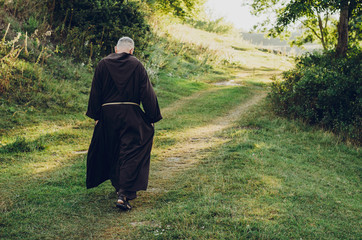 a Catholic  monk in robes praying in the woods. Copy space