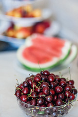 Appetizing ripe juicy cherries in a transparent bowl on the table. A photo with a blurred background.