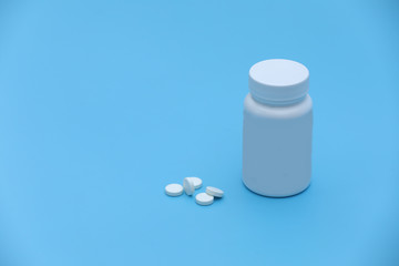Pills spilling out of pill bottle syringe and thermometer on blue background. Virus protection concept. Flat lay, top view, copy space