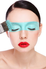 Portrait of young beautiful woman with fancy makeup and painting brush