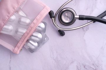Close up of blister pack and stethoscope on tiles background.