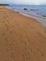 Seascape with waves, sand and river on the beach. Ideal holiday illustration for tourism advertising industry. People s tracks on coast line