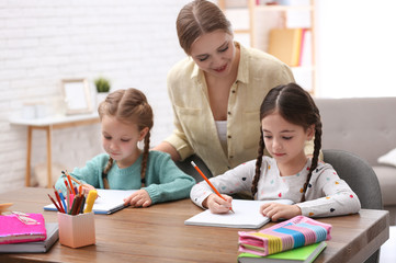 Fototapeta premium Mother helping her daughters with homework at table indoors