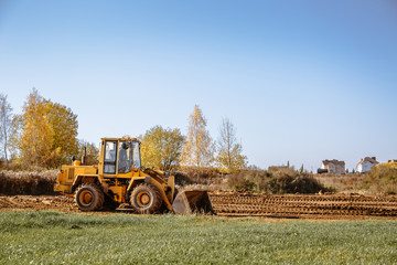 large yellow wheel loader aligns a piece of land for a new building. Preparation of the land for...
