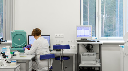 Woman working in a laboratory on a modern machine for blood testing. Doctor checks the blood of the patients. Blood research in a modern scientific workplace.