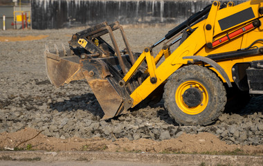 Yellow wheel loader Excavator machine working at construction site with a sand and gravel. Preparing of the fundament for a asphalting. Road construction site. Building of a parking.