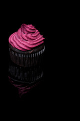 Vegan chocolate and blackcurrant cupcakes. Dark muffins with cashew nuts and black currant cream on top.  Black mirror background with reflection