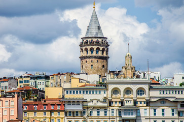 Fototapeta premium Galata Tower. View of famous historic landmark across Golden Horn. Galata bridge with fishermen. Popular tourist destination. Cloudy. Clear blue water. Turkey, Istanbul