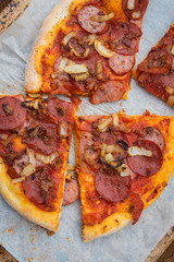 Dairy-free rustic thin crust homemade pizza with pepperoni, bacon, farmer's sausage and caramelized onions