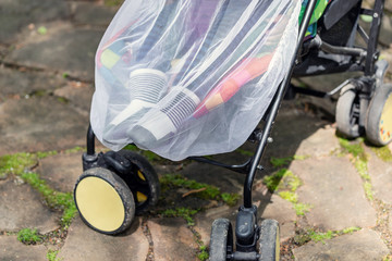 Child in stroller covered with protective net during walk. Baby carriage with anti-mosquito white...