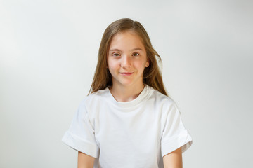 Pretty smiling joyfully girl with fair hair, dressed casually, looking with satisfaction at camera, being happy. Studio shot of good-looking beautiful teenager isolated against blank studio wall.