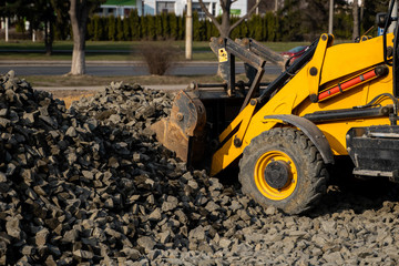 Yellow wheel loader Excavator machine working at construction site with gravel. Preparing of the fundament for a asphalting. Road construction site. Building of a parking.