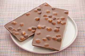Delicious milk chocolate with hazelnuts on wooden background
