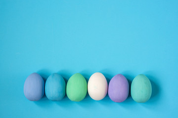Multicolored eggs of bed colors on a blue background