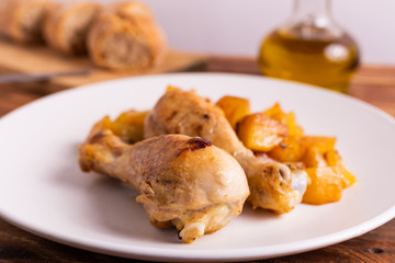 Roasted chicken legs with potatoes on a wooden table