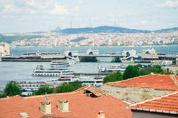 Fototapeta na wymiar Touristic boats in Golden Horn bay and view on Galata bridge and Suleymaniye mosque. View of old city, mosque, red tile roofs and green trees. Popular destination. Turkey, Istanbul