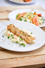 chicken kebab with rice and salad on the wooden background