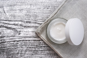 Facial cream on the cotton napkin on the wooden background.