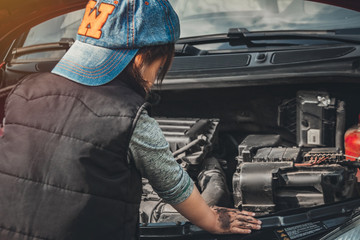 Little child trying to fix broken real car. Dreaming to be auto technician. View from the back