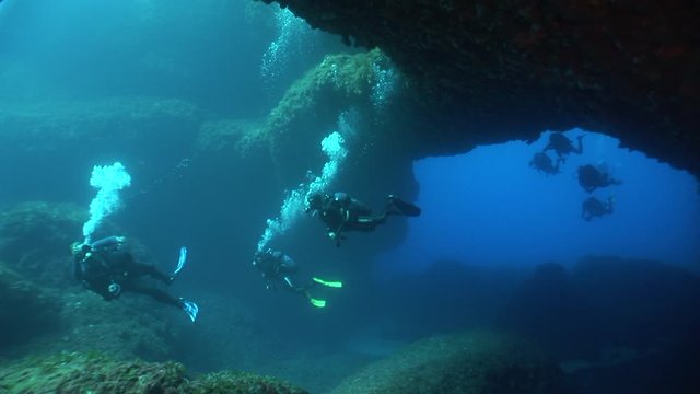 scuba divers exploring the landscape and  arch underwater topography ocean scenery
