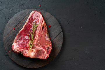 Raw t-bone steak with rosemary, pepper. Prepared for cooking. Close up.