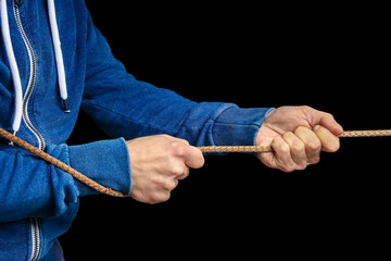 a Hands with a rope on a black background. A man pulls a rope wrestling. Drag the business to your side.