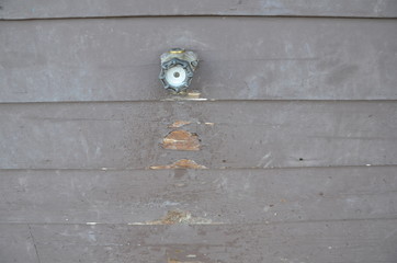 damaged brown wood wall with hose spigot
