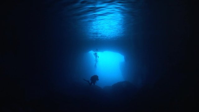 silhouette of scuba divers exploring the blue caves underwater ocean scenery