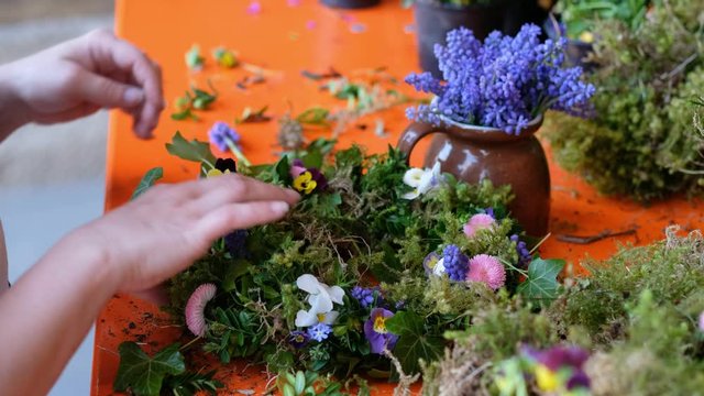 H&auml;nde einer Frau binden einen Blumenkranz im Fr&uuml;hling