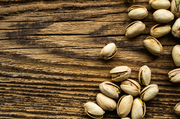 Pistachios scattered on the wooden vintage table. Pistachio is a healthy vegetarian protein nutritious food. Pistachios on rustic old wood.