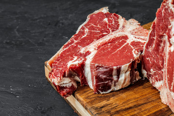 Raw T-bone steak cooking on stone table.