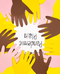 paper hands and a white pad with the inscription plan of a pandemic. the concept of building a different plan because of the coronavirus pandemic