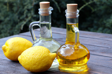 Olive oil and sunflower oil in decanter on a brown wooden table. Limons on a wooden background....
