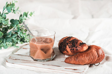 A cup of cold espresso coffee with cream and waffle tubule with chocolate filling in bed. Sweet breakfast, copy space for your text