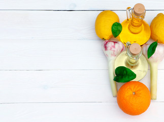 Olive oil and sunflower oil in decanter on a white wooden table. Limons, orange and garlic on a...