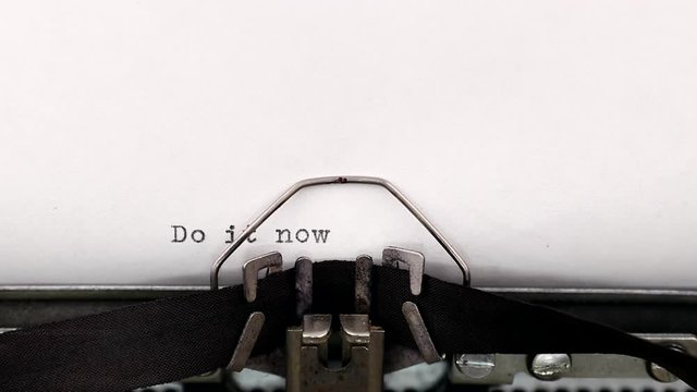 Typing a motivational quote do it now on a vintage typewriter. Concept of inspiration and management encouragement