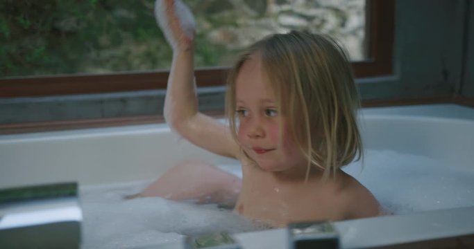 Preschooler in bathtub with his mother putting bubbles on his head