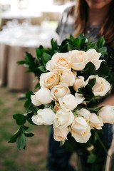 Florist woman holding white roses for decoration of wedding arch. Outdoor wedding party in hotel.