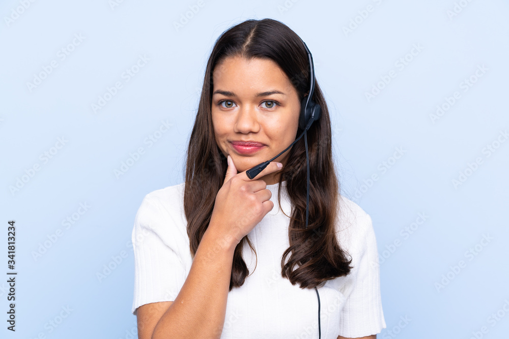 Wall mural young telemarketer colombian woman over isolated blue background laughing