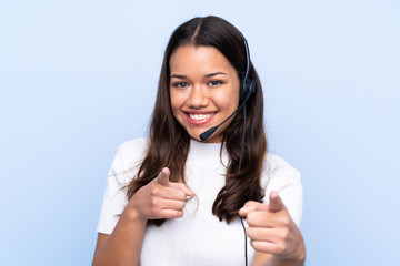 Young telemarketer Colombian woman over isolated blue background points finger at you - obrazy, fototapety, plakaty